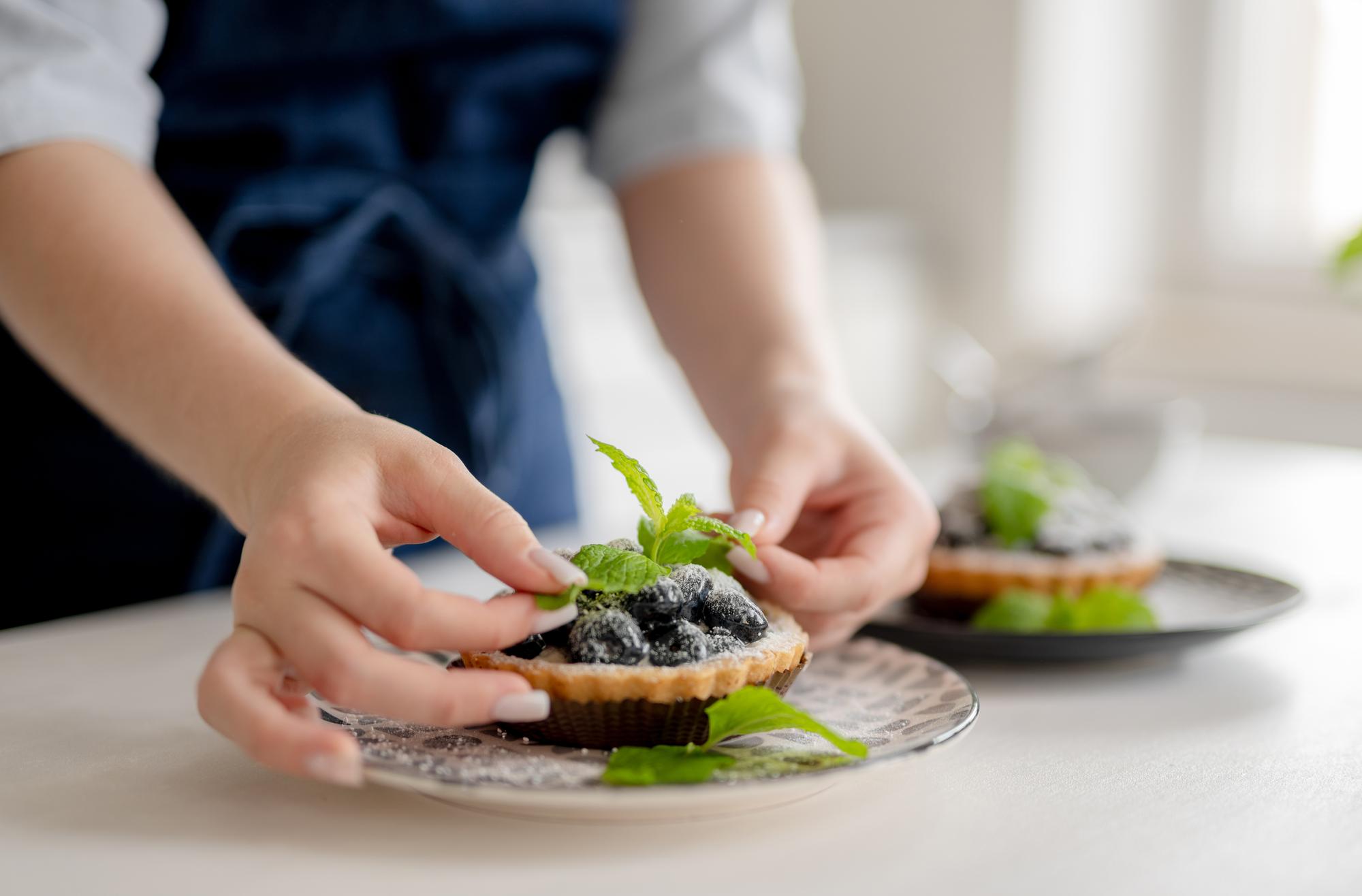 Hands finishing dessert with micro herbs